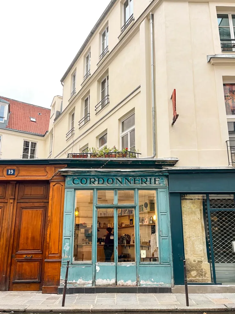 charming old-school blue-wood facade with cordonnerie written at the top housing boot cafe in paris