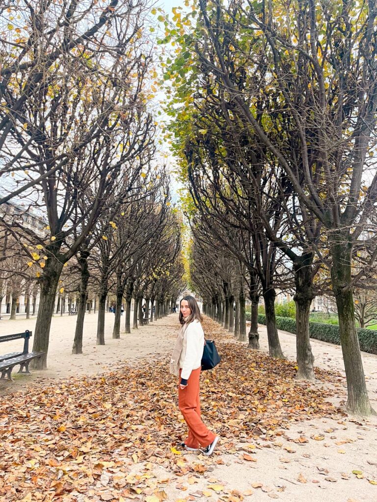 Woman standing in autumn leaves in Jardin du Palais Royal in Paris