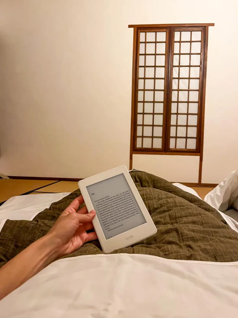 View of someone laying down on tatami mats reading a kindle inside a traditional ryokan