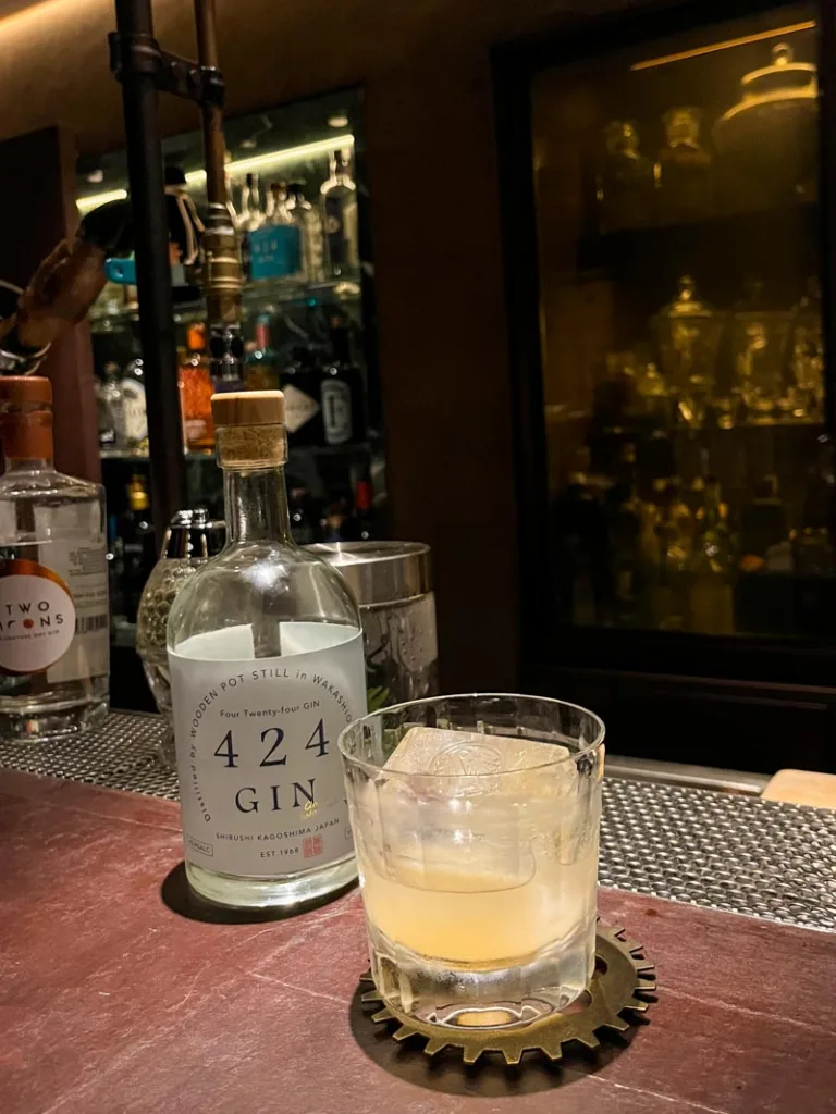 A gin cocktail and the gin bottle next to it on the bar of Bar Juniper in Osaka
