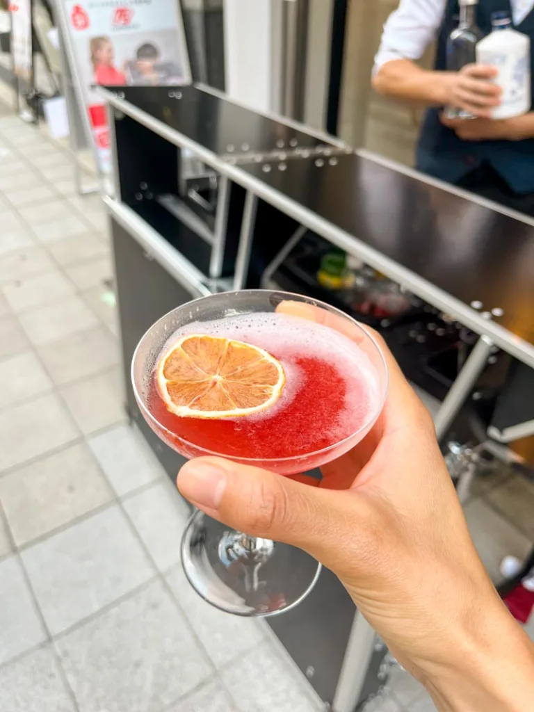 Hand holding a cocktail outdoors at Cafe Tales in Osaka