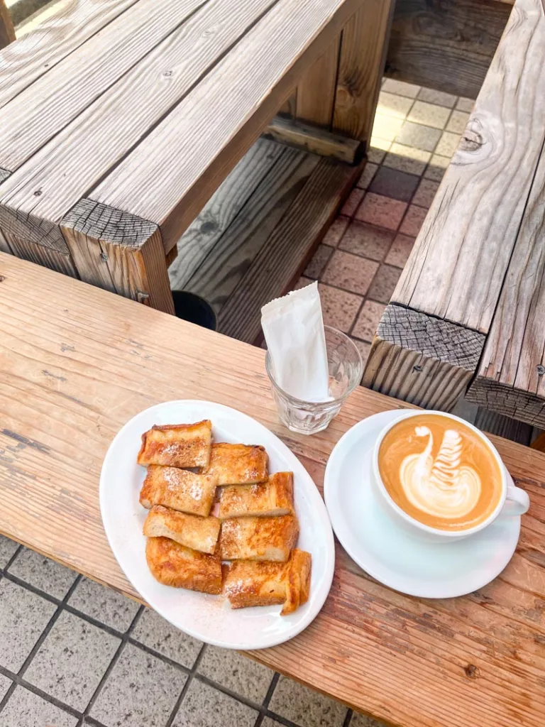 french toast and a latte on a wooden bench at mill pour coffee in osaka
