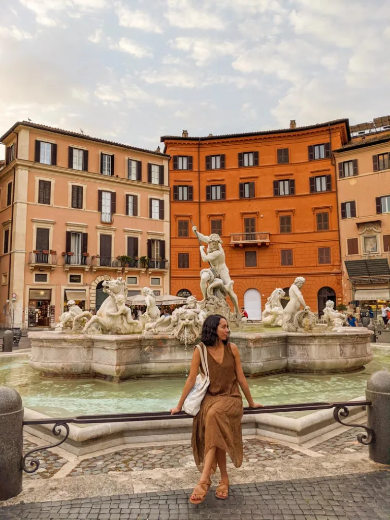 Woman sitting in front of a fountain in Piazza Navona in Rome