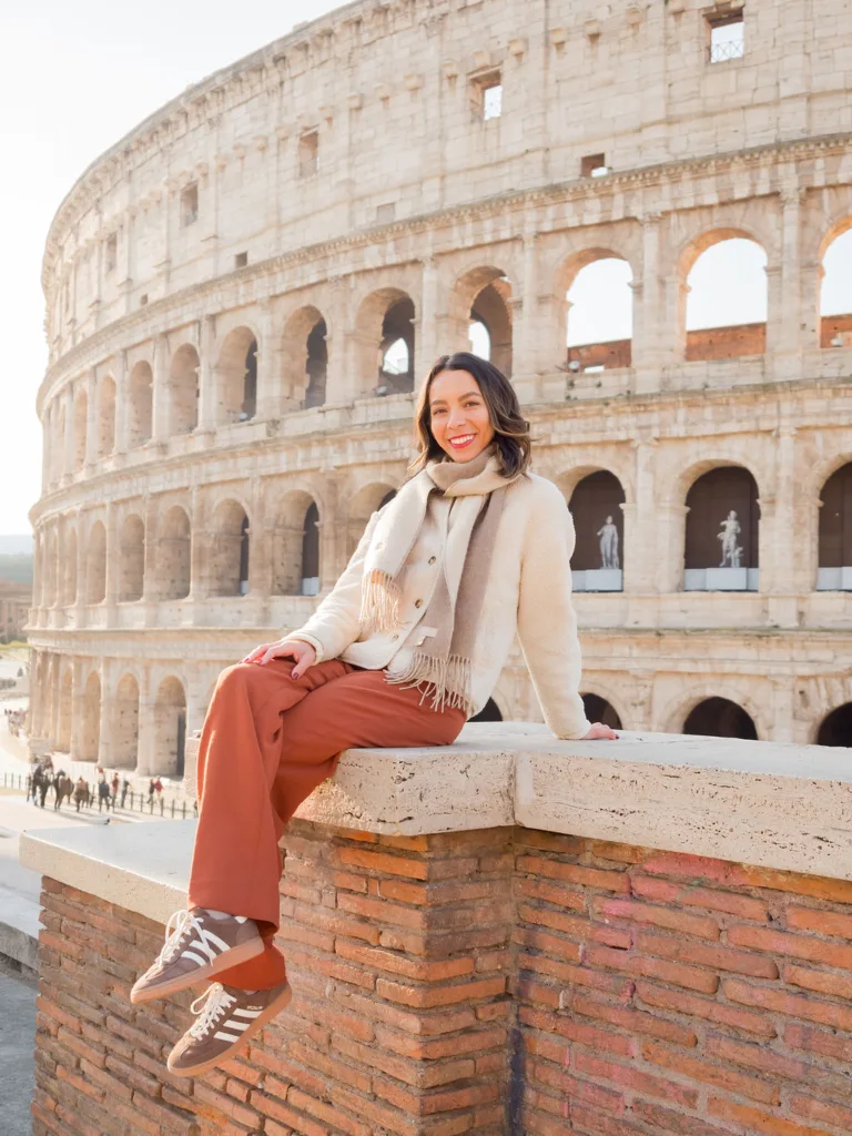 Woman sitting on a wall in front of the Colosseum