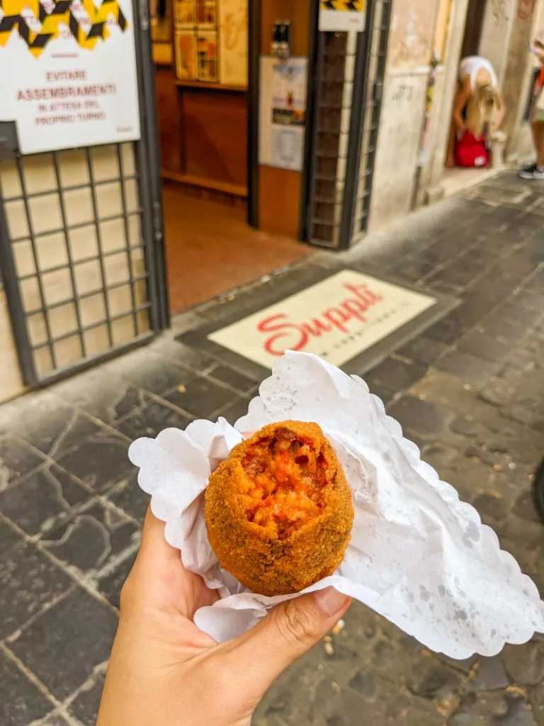 Bitten suppli, showing its red-saucy rice inside