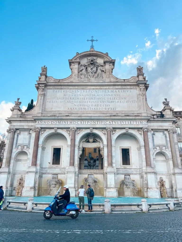 Scooter riding in front of the grand Fontana dell'Acqua Paola in Rome