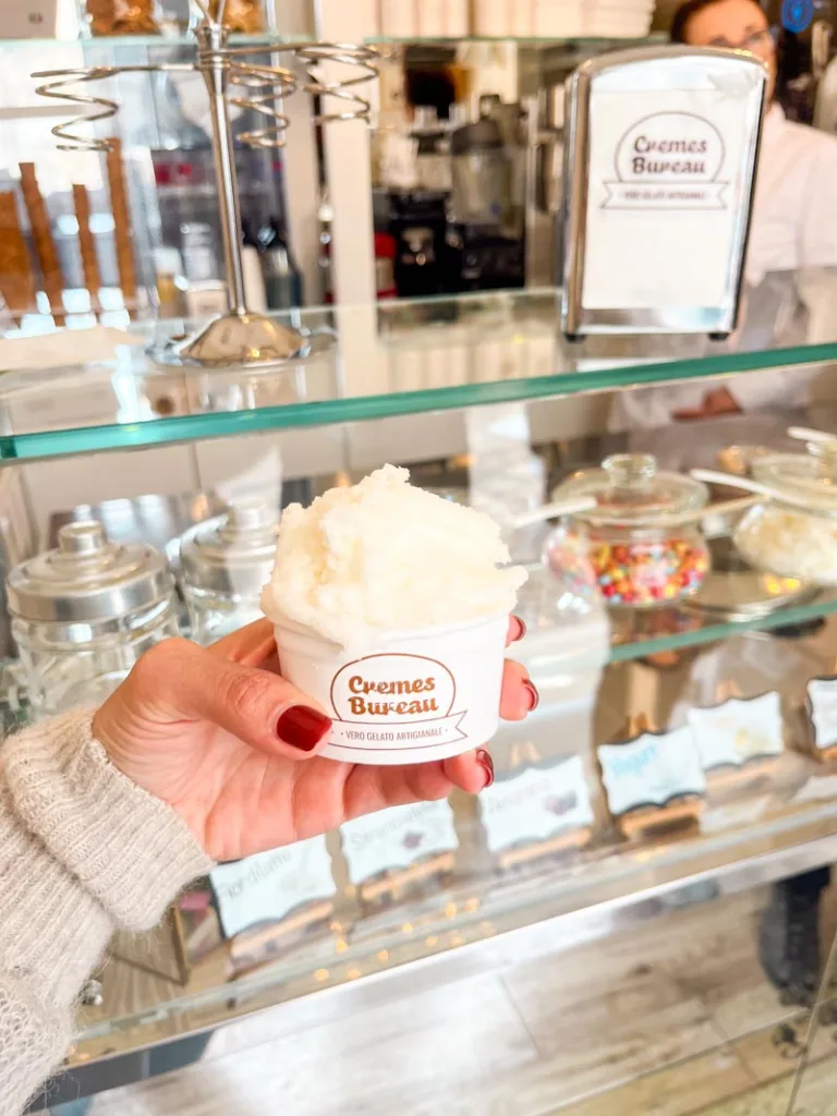 Hand holding a cup with gelato at Cremes Bureau in Matera, Italy