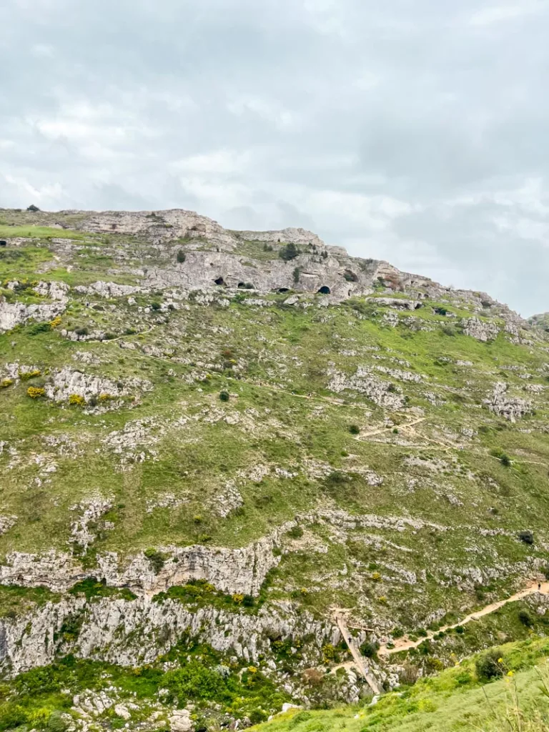 Green hills dotted with caves across the gorge in Matera, Italy