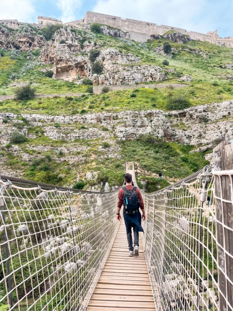 Men crossing the Ponte Tibetano della Gravina in Matera, Italy