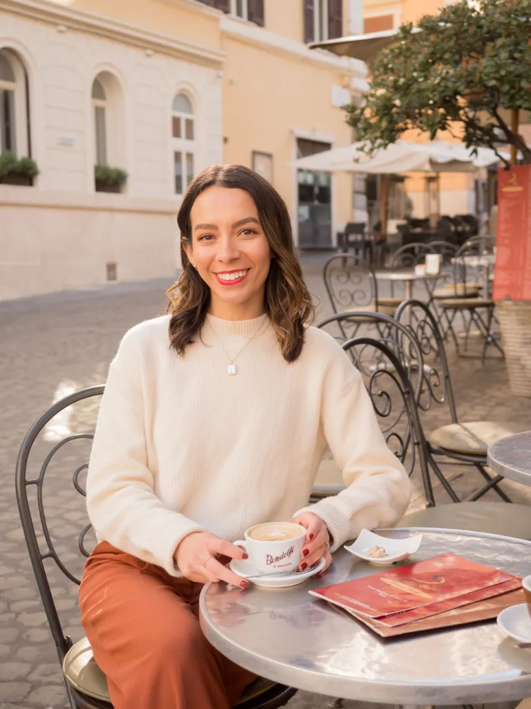 Woman sitting at an outdoor table at La Bottega del Cafe with cappuccino in hand in Monti, Rome