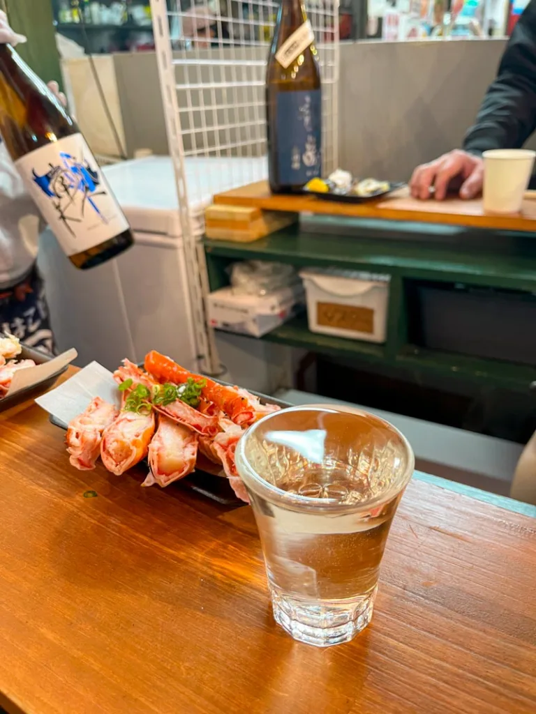 sake and crab legs at a sushi standing bar at ameyoko shopping street in ueno tokyo