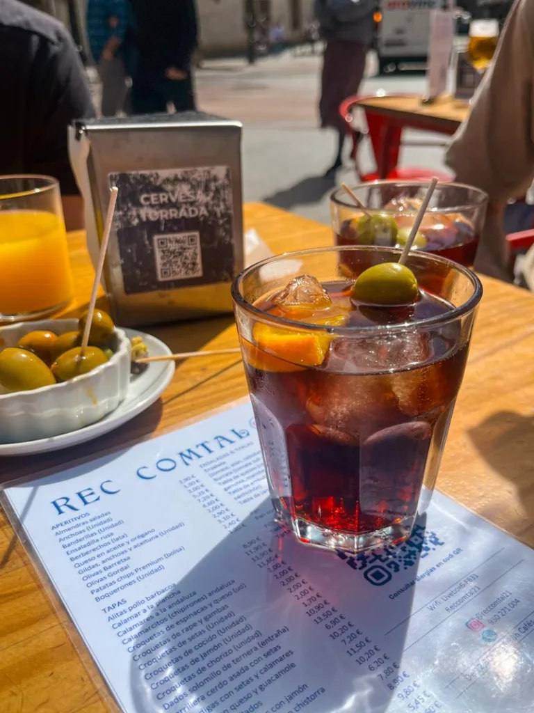 two vermut glass and a plate of olives on a table at rec comtal 21 bar in barcelona