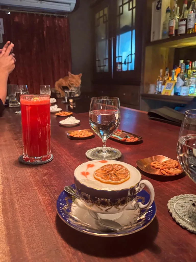 wooden bar with cocktails on it, and a cat napping at the other end of the bar