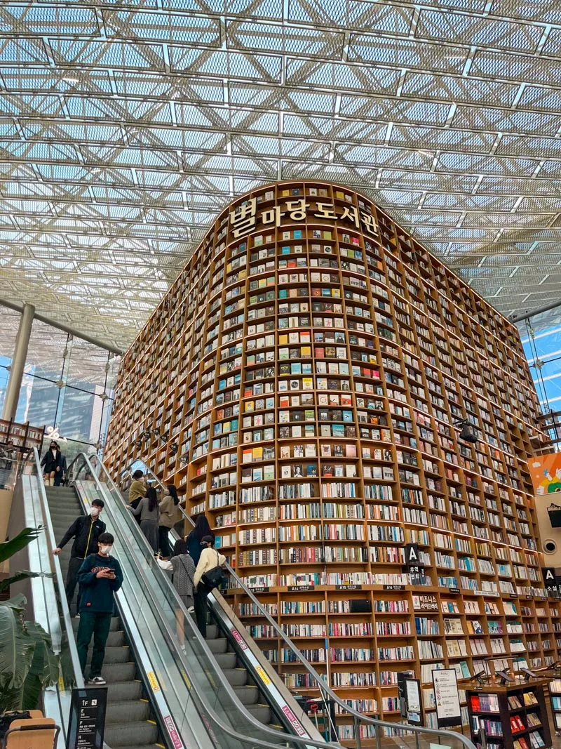floor to ceiling bookshelves and the electric stairs in front of them at coex library in seoul