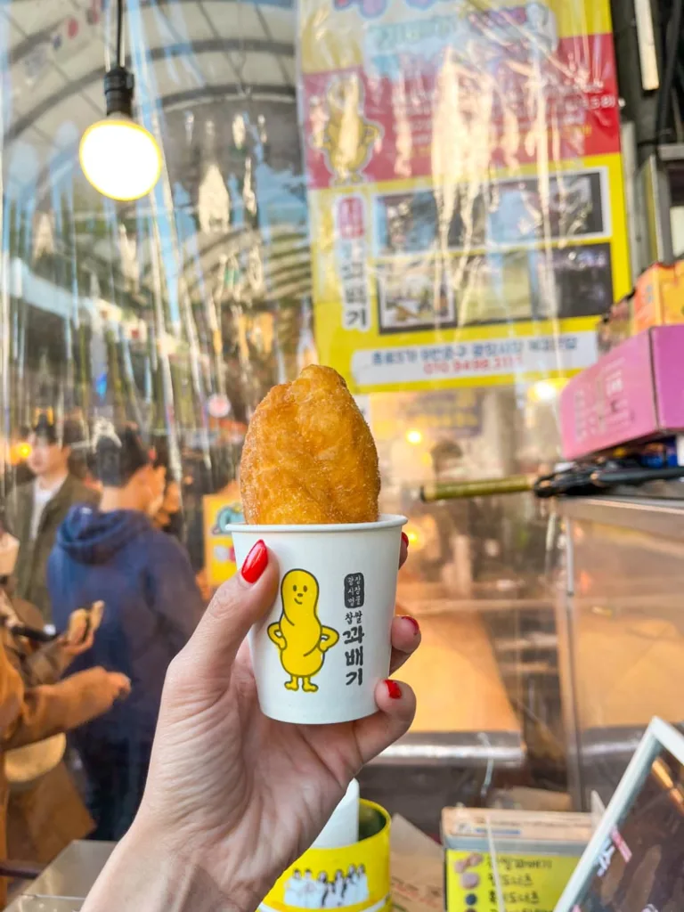 hand holding a korean twisted donut in a cup at gwangjang market in seoul