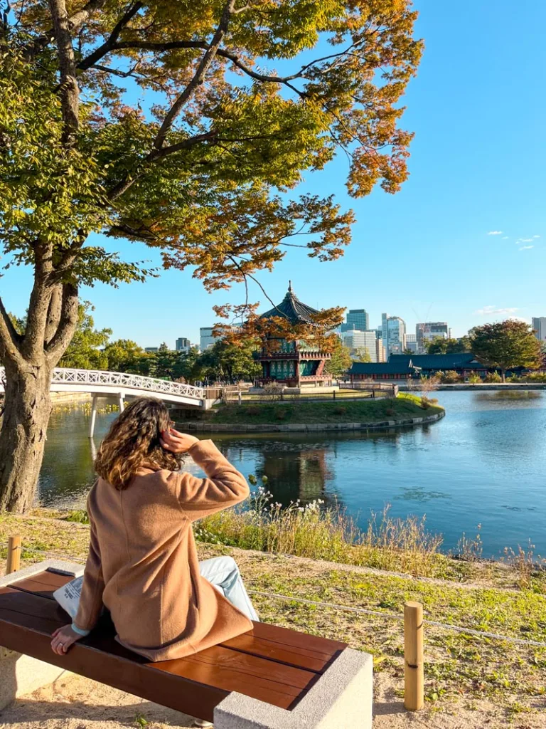 woman sitting on a bench looking at the gyeongbokgung palace's pond in seoul