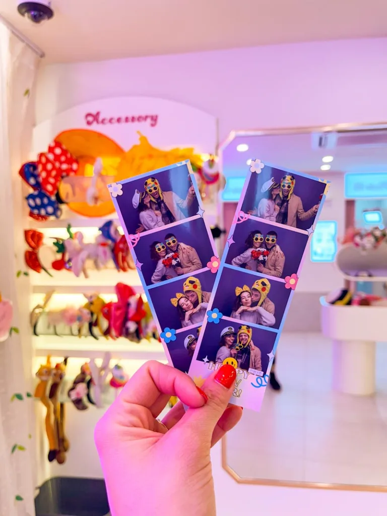 hand holding two strips of printed photos from a korean photobooth in seoul