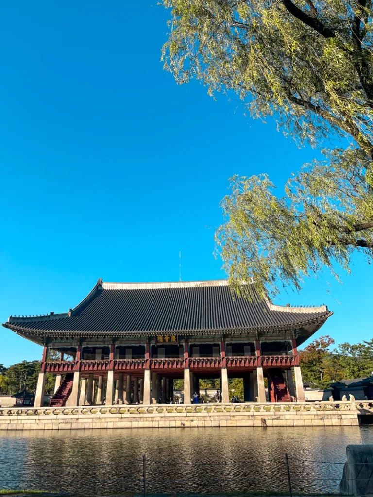 Gyeongbokgung Palace pavilion by the water on a sunny day in Seoul, with clear blue skies and reflections in the pond.
