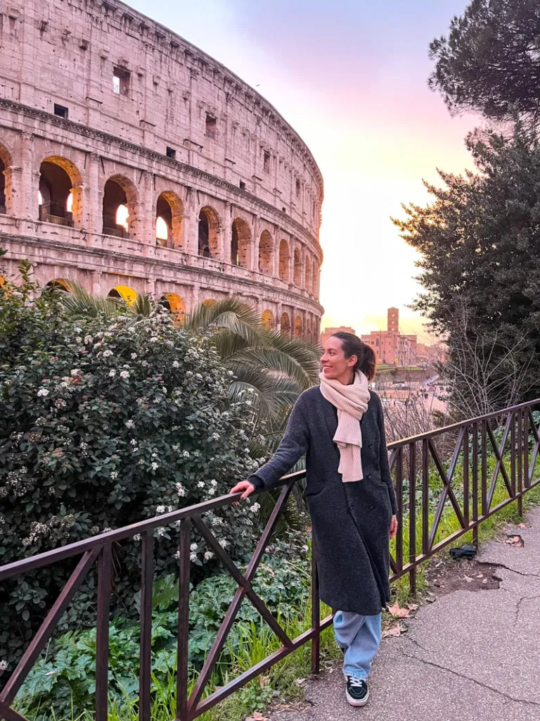 Woman standing in front of the colosseum in rome with color candy skies at the back