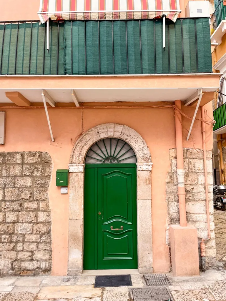 peach-colored house with a forest green door and mail box in bari vecchia