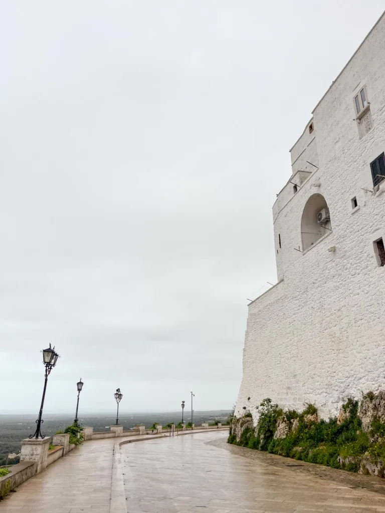 view from the cinta muraia in ostuni on a cloudy day, overlooking green fields and the clouds in the distance