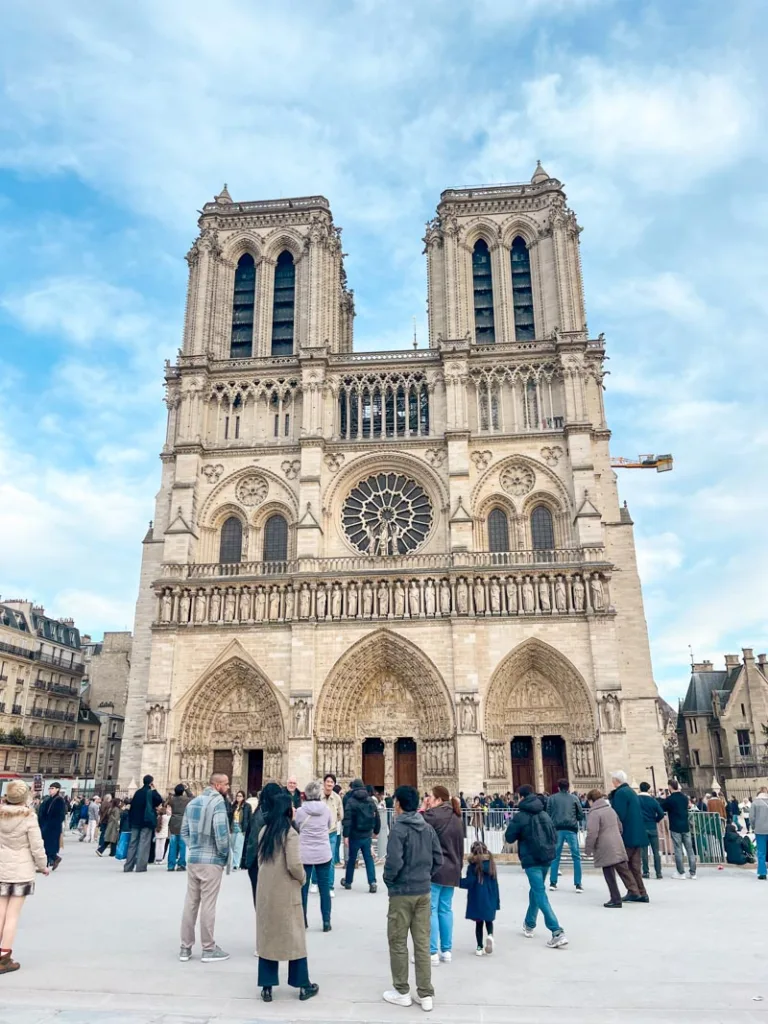 front view of notre dame cathedral in paris and lots of people in front