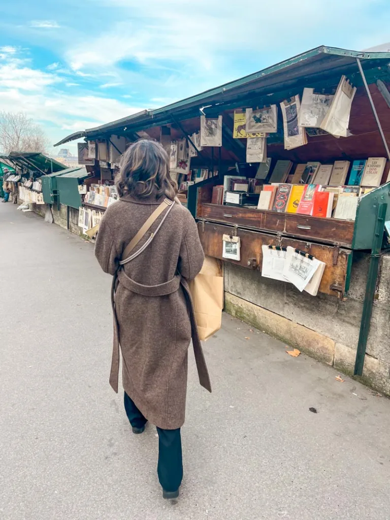 woman looking at books at the famous green stands along the seine river in paris