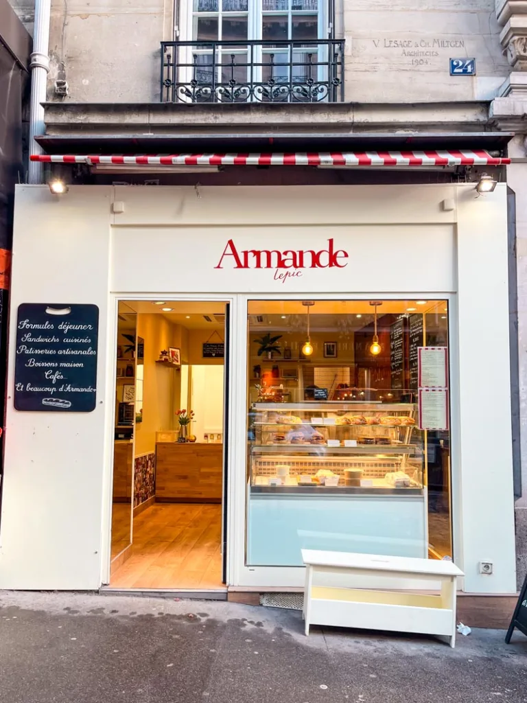 cream-colored facade of armande bakery in paris, with a thin red letter sign