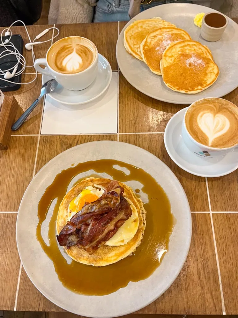 two plates with stacks of pancakes, and two cappuccinos at coutume coffee shop in paris