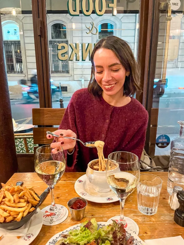 woman enjoying a french onion soup at a restaurant in paris