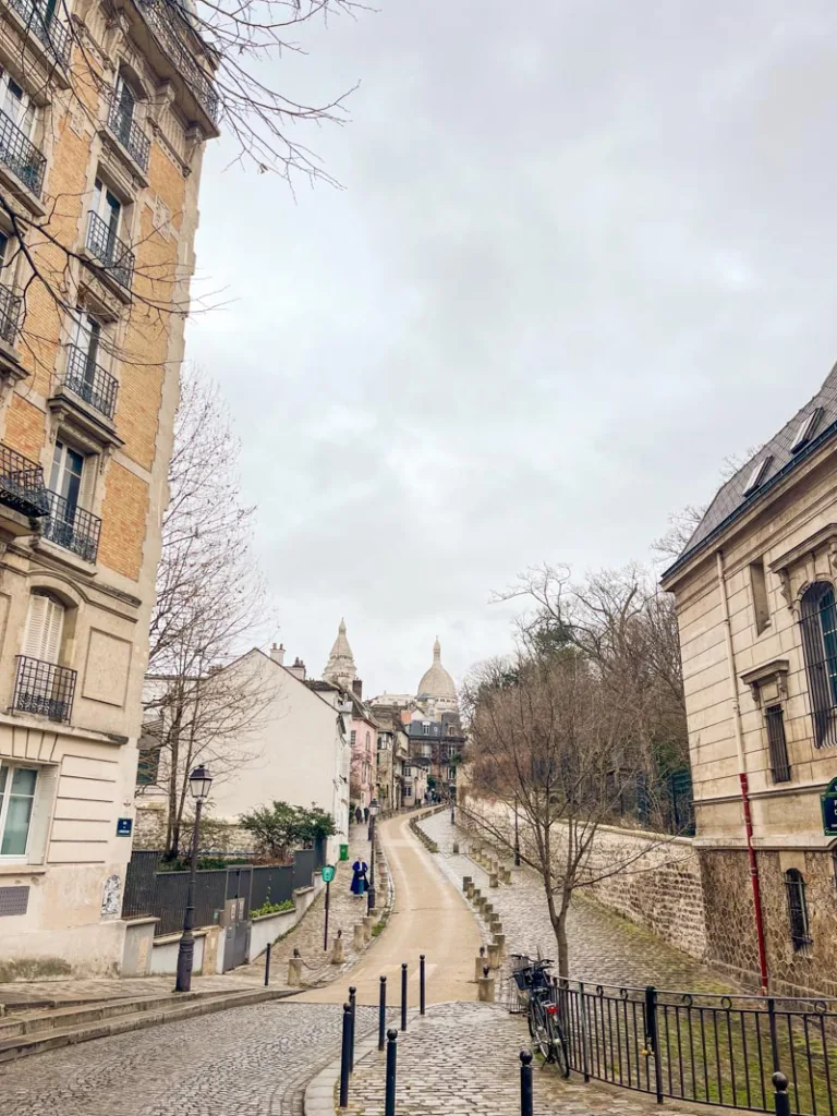 view of rue de l'abrevoir in montmartre, with the dome of sacre coeur at the back