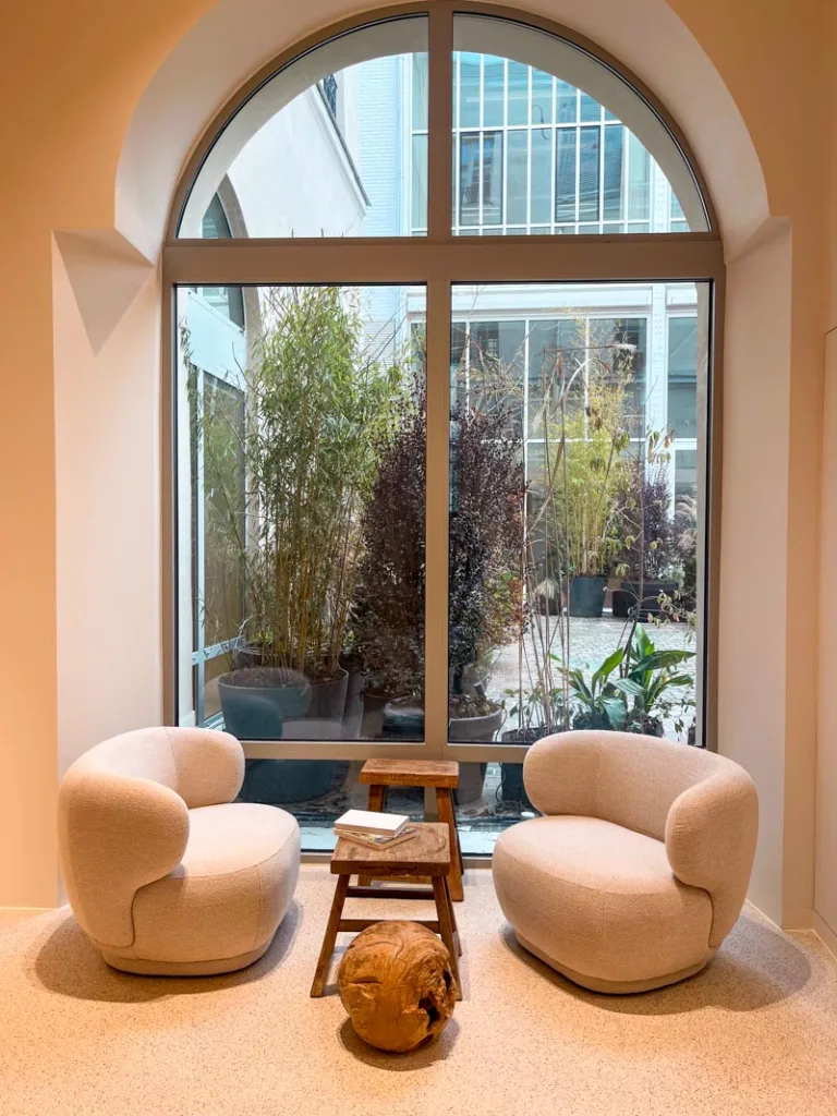 two cozy cream-colored arm chairs next to a big window at the caudalie spa in paris