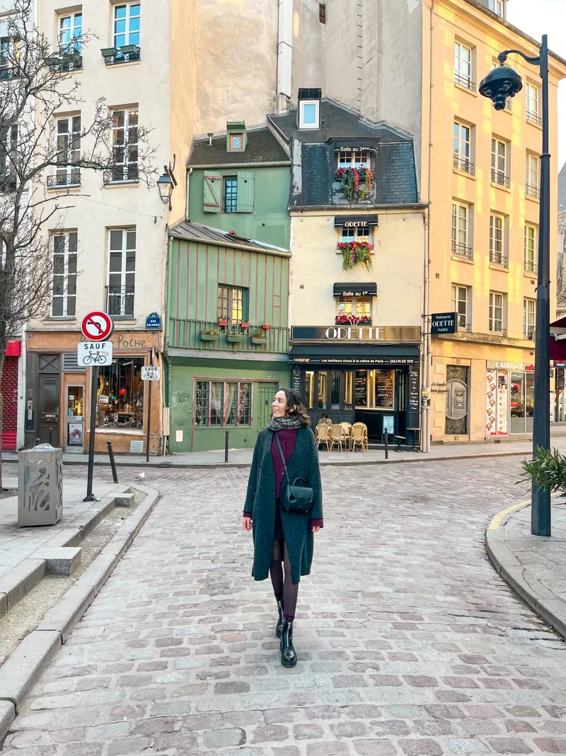 Woman walking through the latin quarter in paris, with a view of the charming odette shop at the back