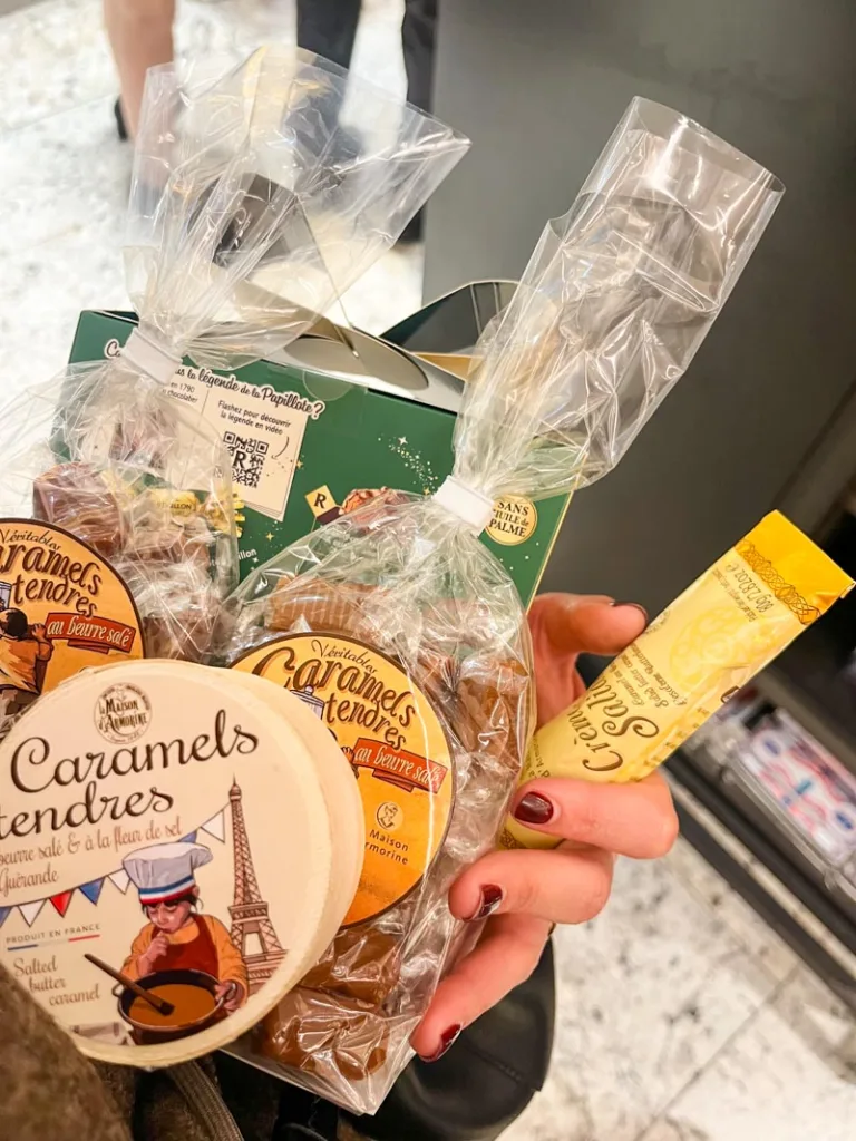 one hand hugging a bunch of salted caramel bcandies and chocolates at la grande epicerie in paris