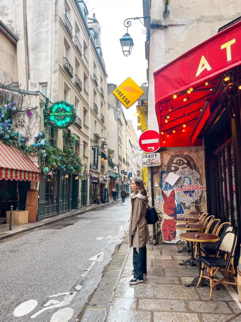 woman standing outside a parisian cafe in le marais on a rainy day