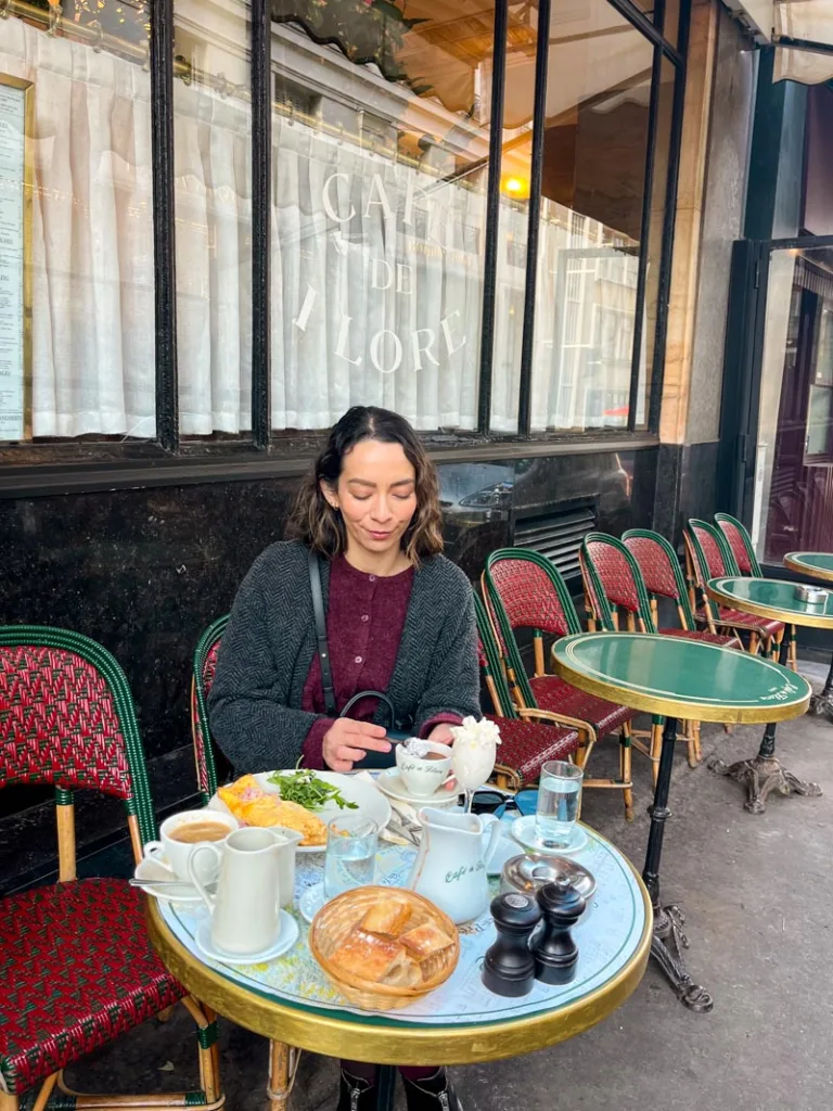 woman sitting on an outdoor table at cafe de flore, one of the best things to do in saint germain, paris