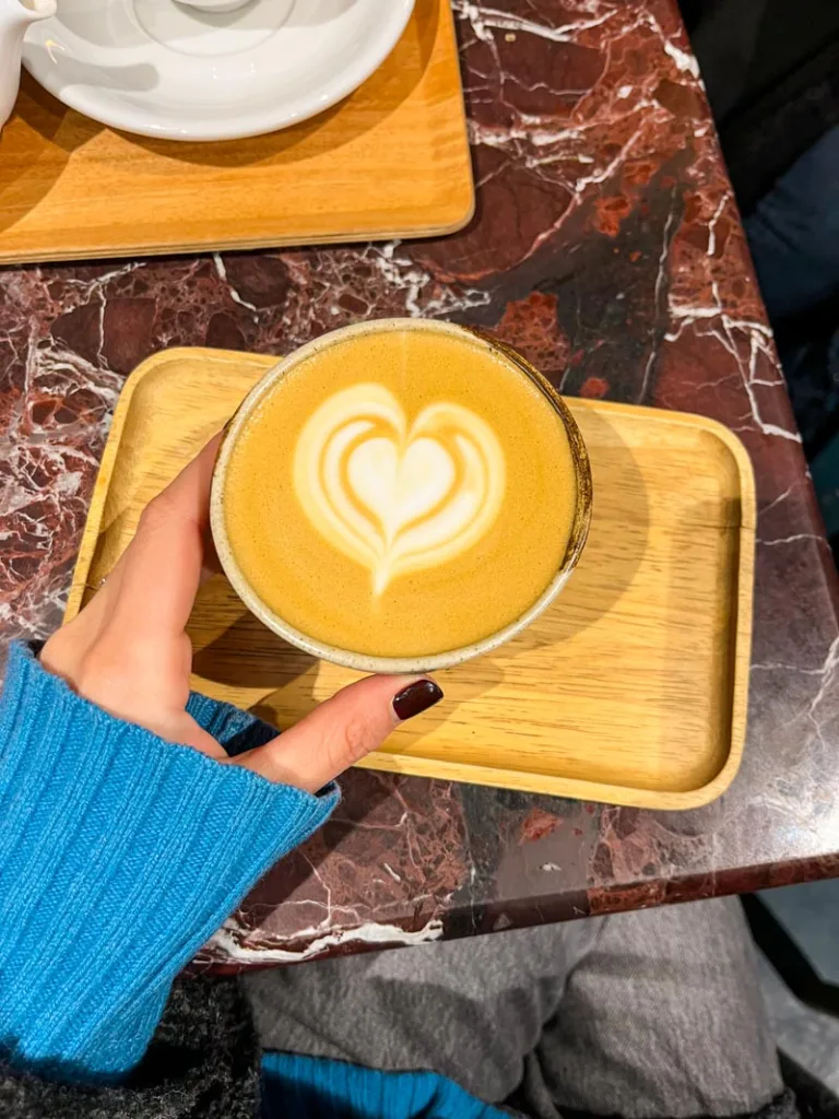 hand holding a cappuccino on a marble table at cafe du clown in saint germain des pres, paris