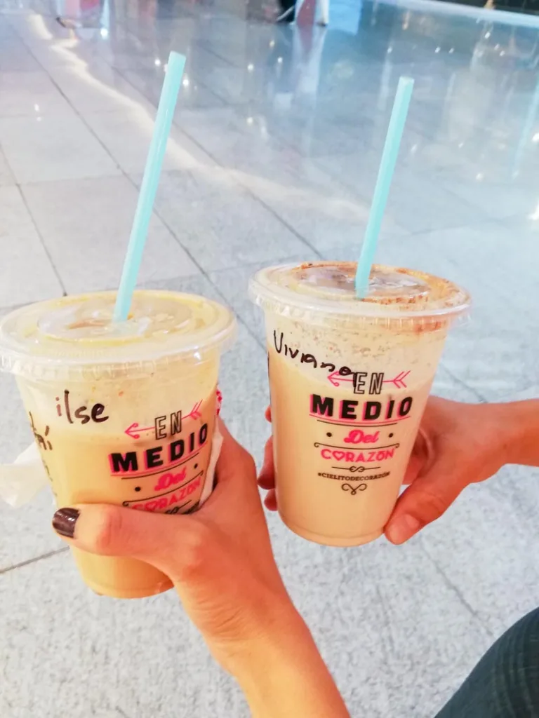 two hands holding iced coffee to go from cielito querido cafe in mexico city