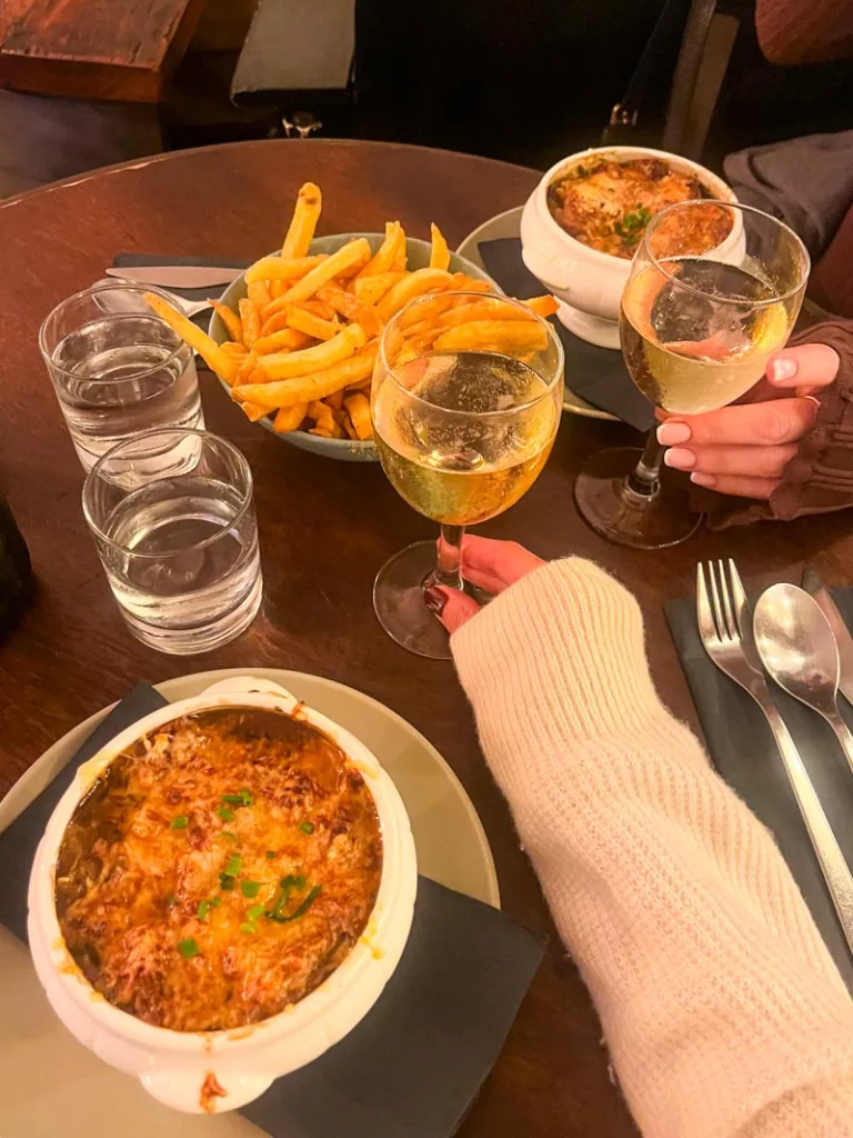 two glasses of wine, two onion soups and a bowl of fries on the table at le balto bistro in saint germain, paris