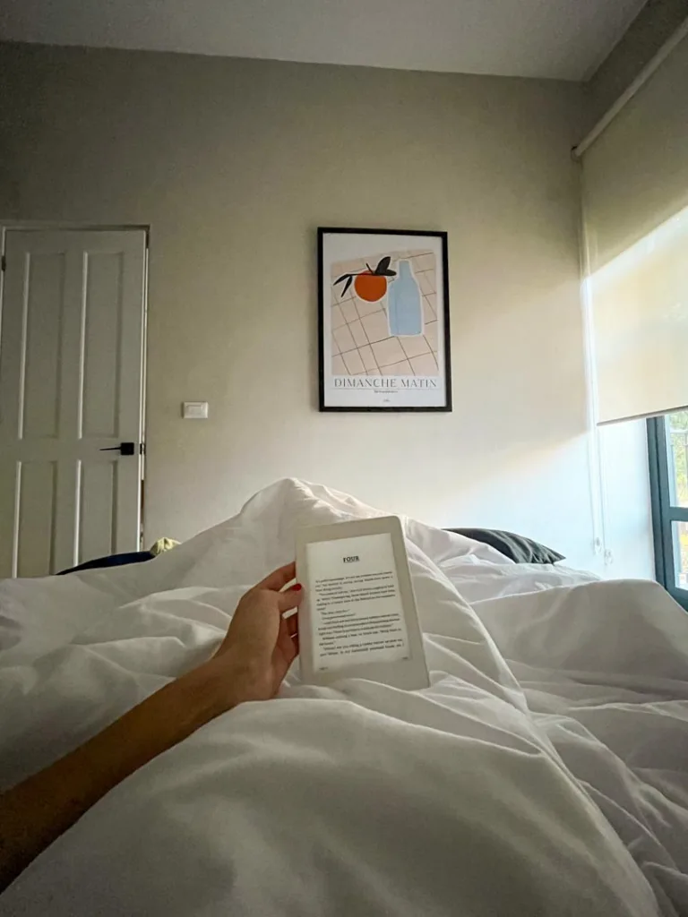 hand holding a kindle in bed in an apartment in mexico city
