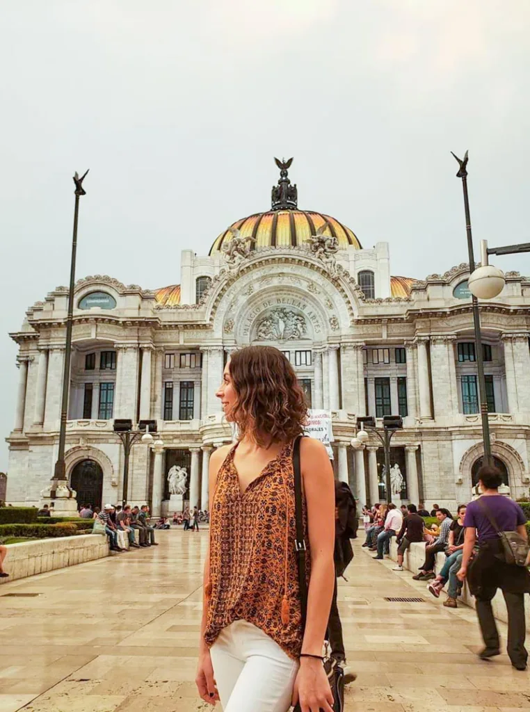woman standing in front of the palace of fine arts in mexico city