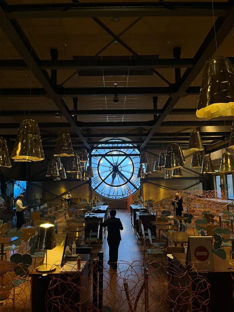 view of the cafe campana with tables looking at the giant clock of musee d'orsay in paris
