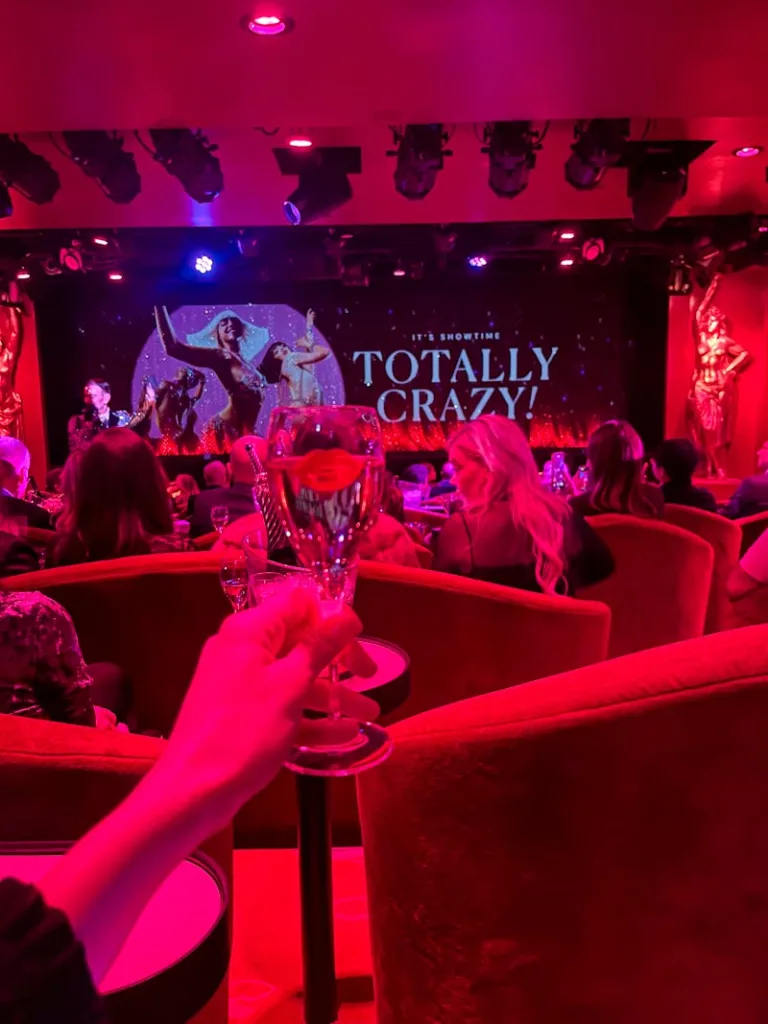 hand holding a champagne glass with a view of the crazy horse stage at the back