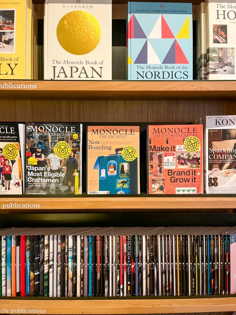 coffee tables books and magazines on display on a bookshelf at monocle cafe