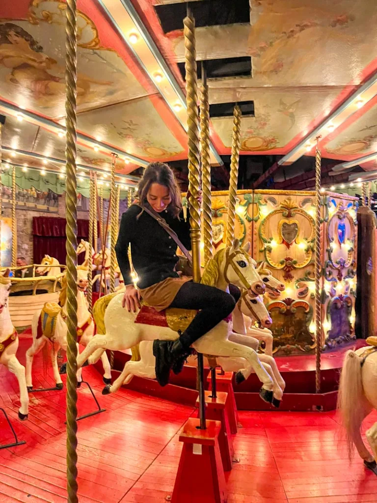 woman sitting on an old carousel horse at the musee des arts forains in paris