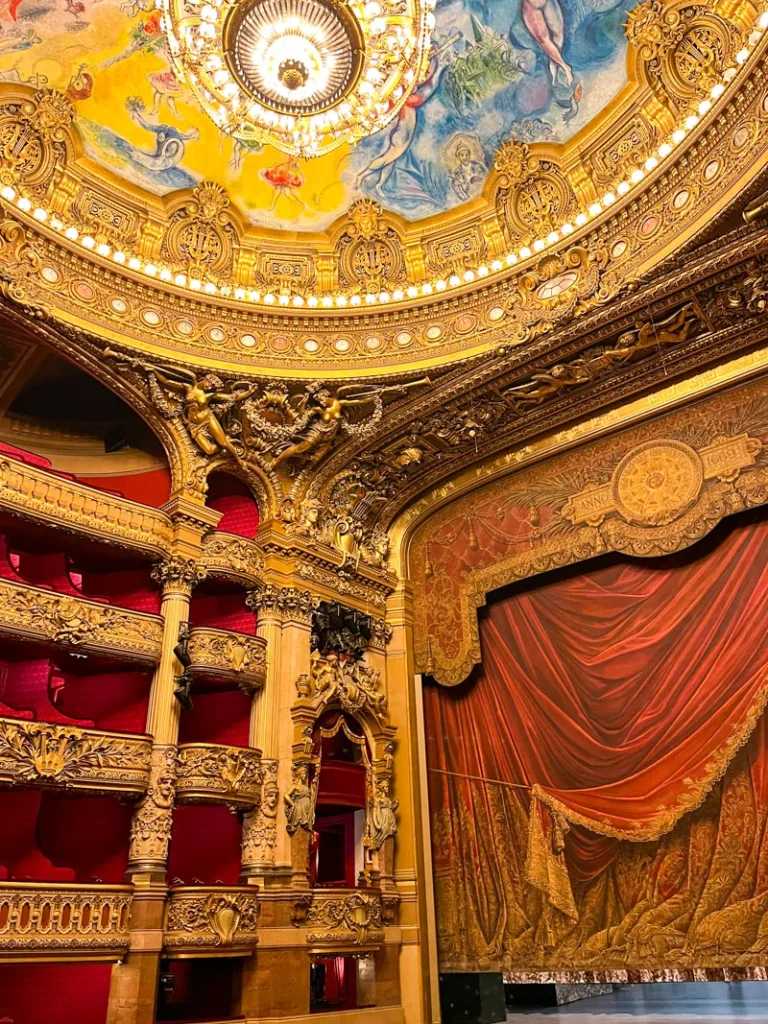 red velvet seats, a red show curtain, and a colorful ceiling at the opera garnier in paris