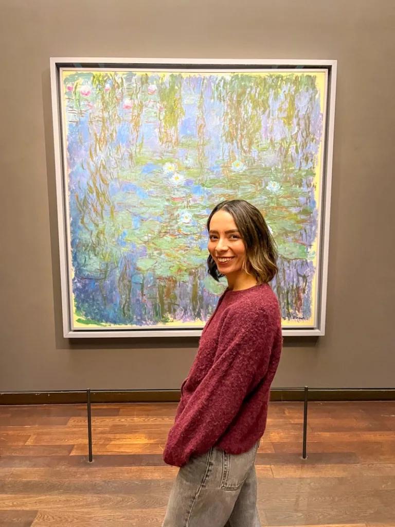 woman smiling in front of monets water lilies painting inside musee d'orsay in paris