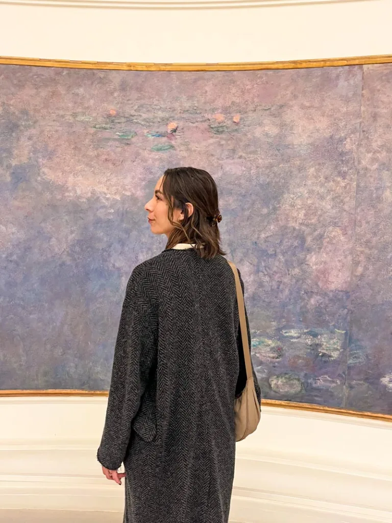 woman standing in front of monet water lilies at musee de l'orangerie with her profile towards the camera
