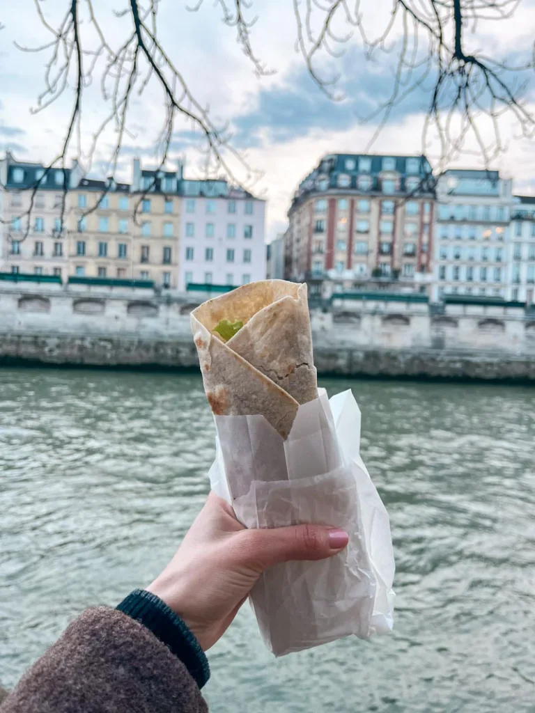hand holding a burrito by the river seine in paris