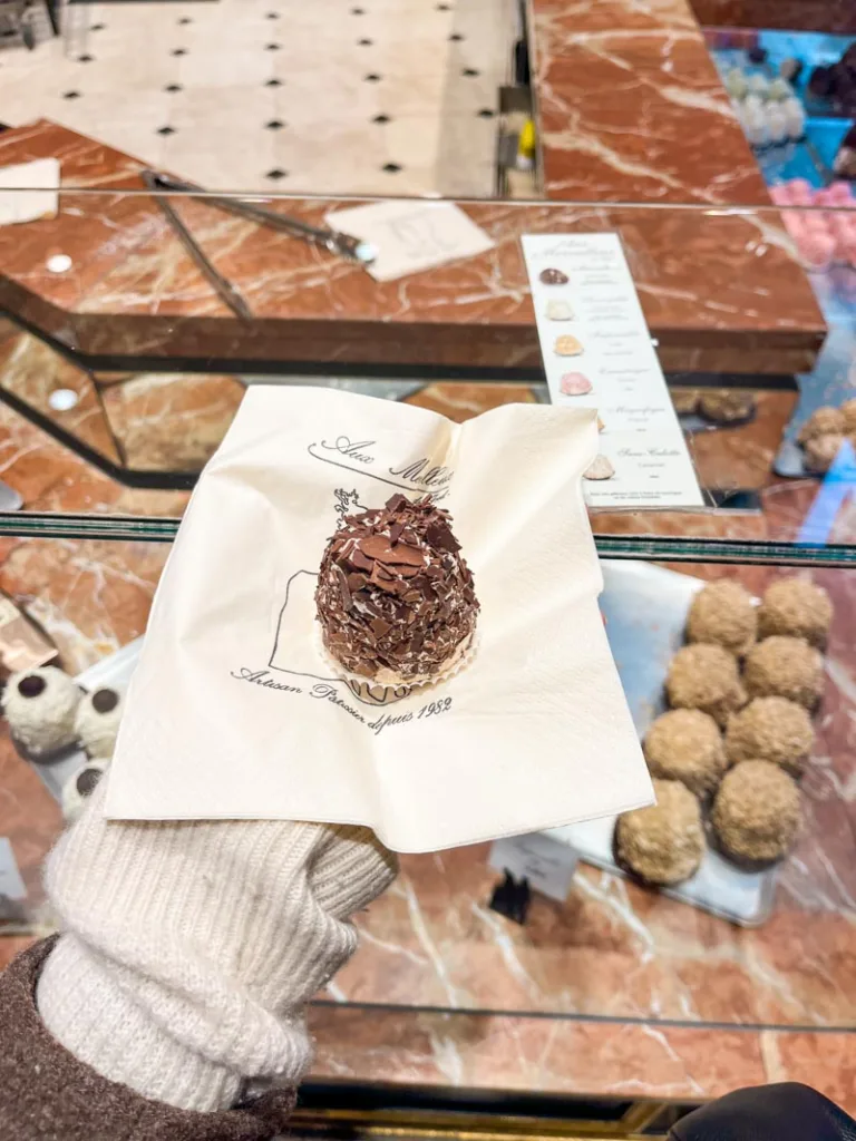 hand holding a small merveilleux at the pastry shop in paris